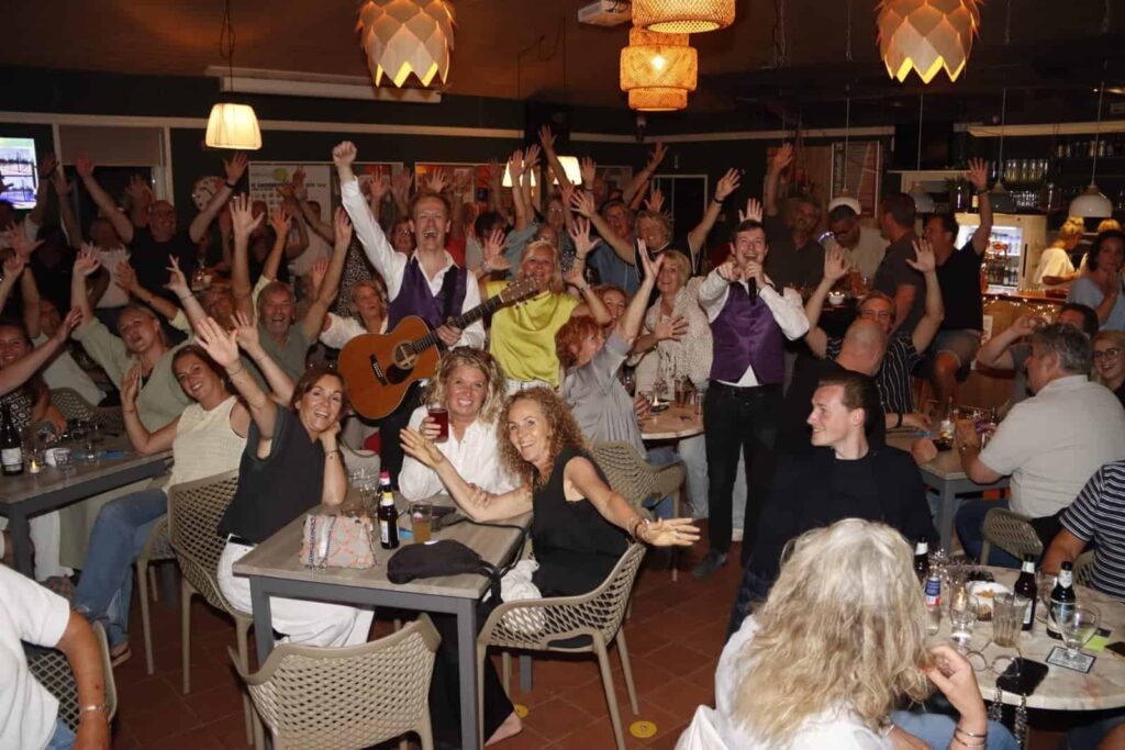 Pubquiz groep feest lachend op de foto met de handen in de lucht