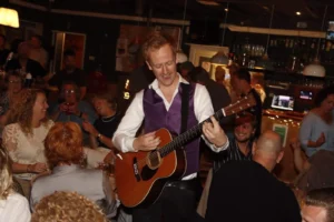 Quizmaster Rens Warnar op gitaar Pubquiz verenigingsfeest